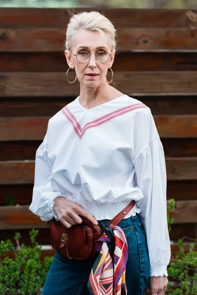 Красива старша жінка позує в стильному вбранні з сумкою для талії — стокове фото