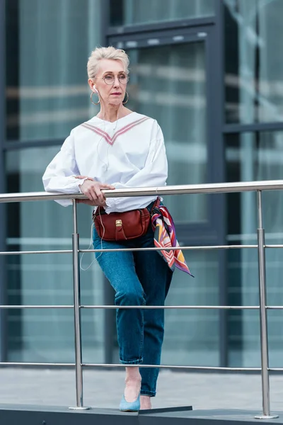 Femme âgée en tenue tendance écouter de la musique avec des écouteurs dans la ville urbaine — Photo de stock