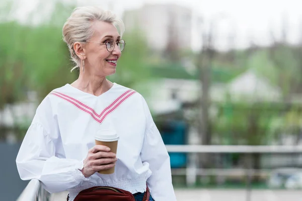 Schöne Seniorin im trendigen Outfit mit Einwegbecher Kaffee im Park — Stockfoto