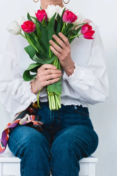 Vista recortada de mujer con ramo de flores de tulipán, aislado en blanco - foto de stock