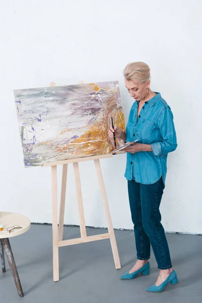 Senior female artist painting in workshop — Stock Photo