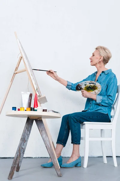 Пожилая женщина на мольберте в художественной мастерской — стоковое фото
