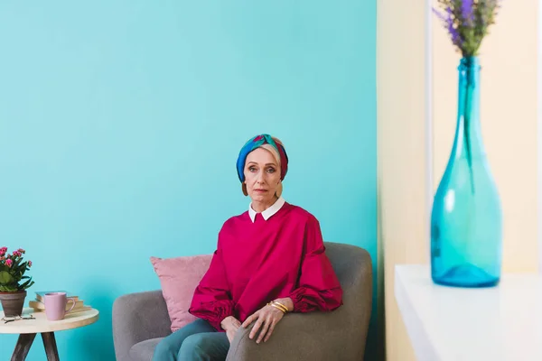 Belle femme âgée assise dans un fauteuil dans une chambre dans un style vintage — Photo de stock