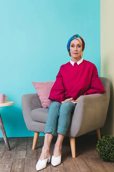 Elegant senior woman sitting in armchair in room in vintage style — Stock Photo