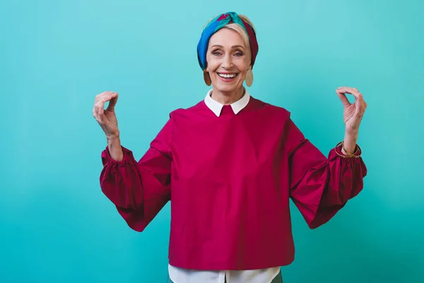 Glückliche Seniorin gestikuliert vereinzelt auf blauem Grund — Stockfoto