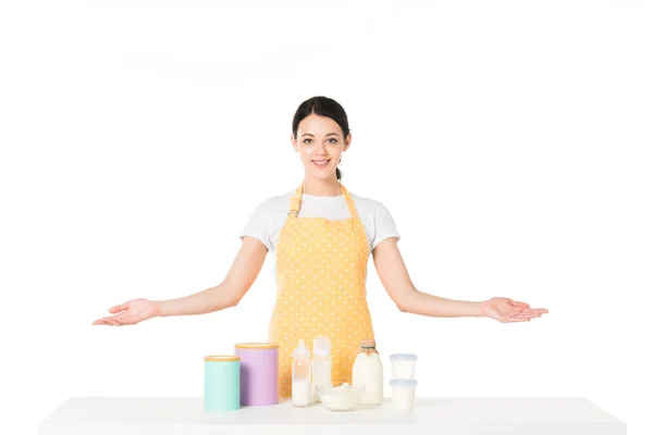 Улыбающаяся женщина с широкими руками, стоящая за столом с детским питанием и молоком на белом фоне — стоковое фото