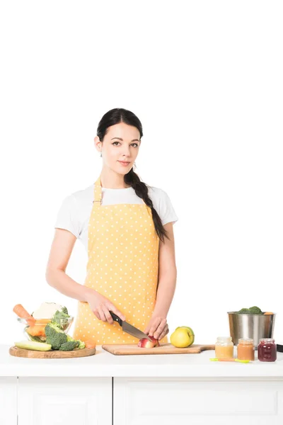Junge Frau schneidet Apfel mit Messer am Tisch isoliert auf weißem Hintergrund — Stockfoto