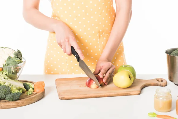 Image recadrée de la femme dans le tablier coupe pomme par couteau isolé sur fond blanc — Photo de stock