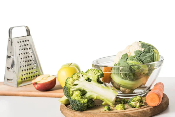Primo piano vista di taglieri, grattugia, ciotola, mele, carote, broccoli e cavolfiore sul tavolo isolato su sfondo bianco — Foto stock