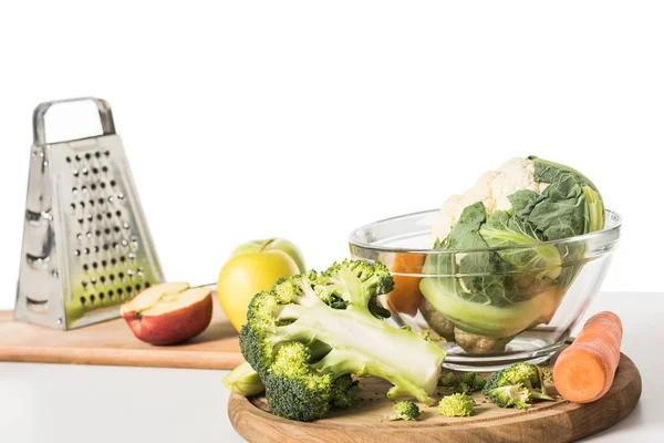 Closeup view of cutting boards, grater, bowl, apples, carrot, broccoli and cauliflower on table isolated on white background — Stock Photo