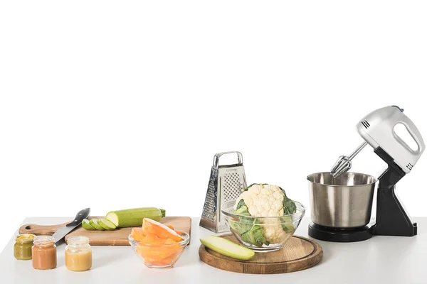 Tablas de cortar, verduras, rallador, licuadora y tazón con coliflor aislada en la mesa - foto de stock