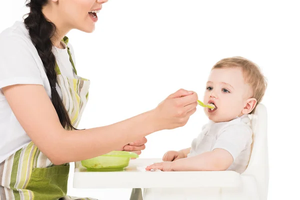 Обрезанный снимок матери, кормящей маленького сына, сидящего в кресле на белом фоне — стоковое фото