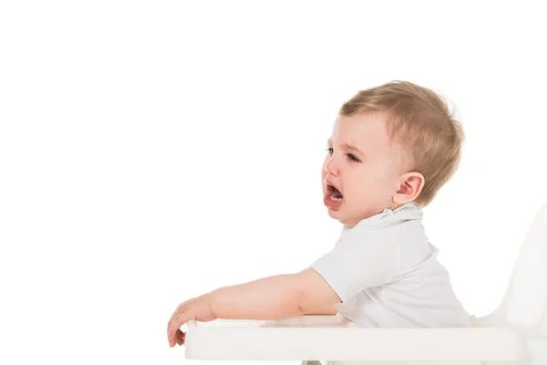 Vista lateral del niño llorando en trona aislado sobre fondo blanco - foto de stock