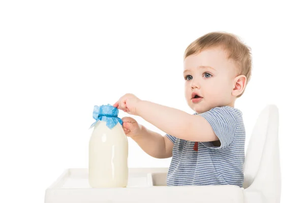 Adorable bebé niño con biberón de leche y silla alta sentado aislado sobre fondo blanco - foto de stock