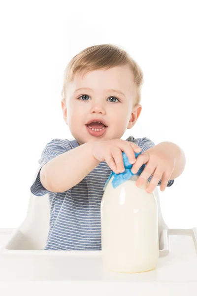 Adorable bebé con biberón de leche sentado en trona aislado sobre fondo blanco - foto de stock