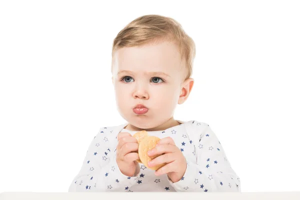 Очаровательный маленький мальчик ест печенье и сидит в кресле изолированы на белом фоне — стоковое фото