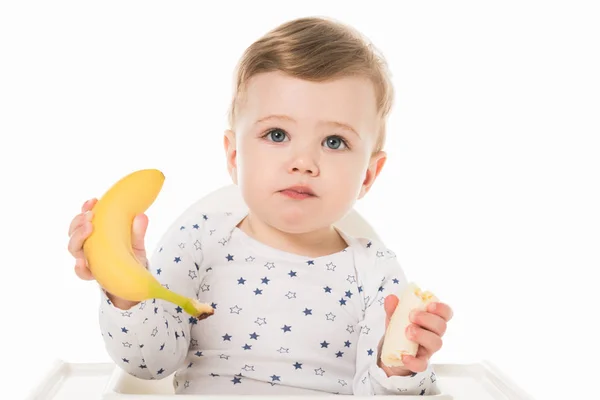 Niño pequeño con plátanos sentado en trona aislado sobre fondo blanco - foto de stock