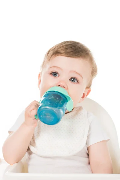 Niño bebiendo agua de la taza del bebé en trona aislado sobre fondo blanco - foto de stock