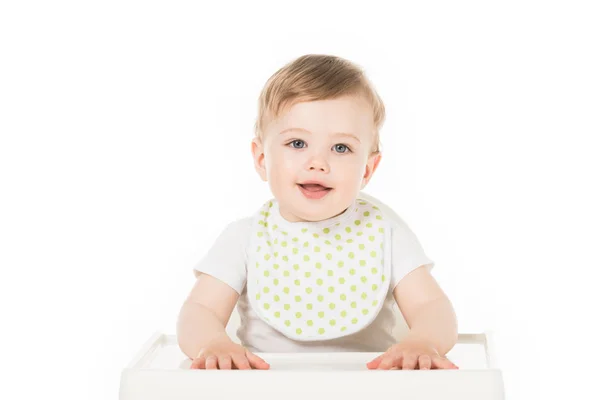 Bébé garçon souriant en bavoir assis dans une chaise haute isolé sur fond blanc — Photo de stock