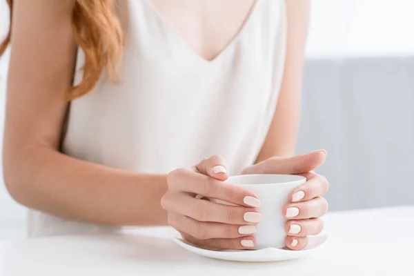 Tiro recortado de la mujer sosteniendo la taza de café - foto de stock