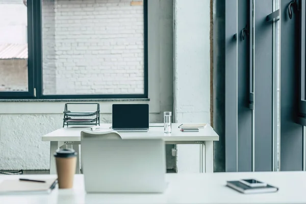 Schreibtische mit Laptops, Coffee to go und Wasserglas, Notizbücher und Dokumententablett — Stockfoto