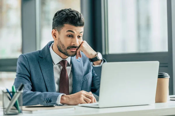 Empresário surpreso olhando para laptop enquanto sentado no local de trabalho — Fotografia de Stock