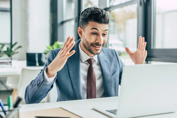 Surprised businessman showing wow gesture while looking at laptop — Stock Photo