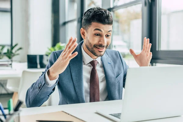 Empresário surpreso mostrando gesto wow enquanto olha para laptop — Fotografia de Stock