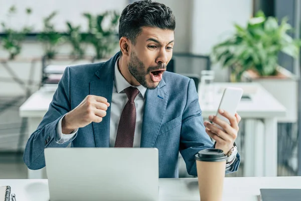 Irritated businessman yelling and showing fist during video chat on smartphone — Stock Photo