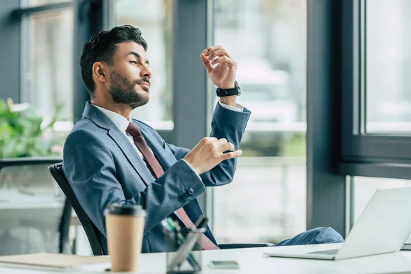 Dreamy businessman imitating playing violin while sitting at workplace — Stock Photo