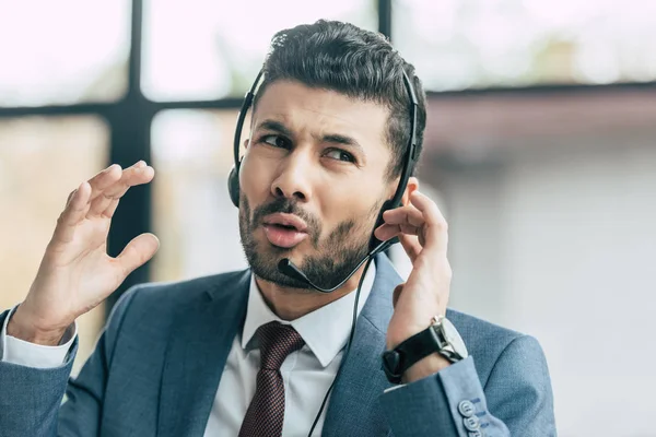 Operador de centro de llamadas disgustado en auriculares que muestran gesto de indignación - foto de stock