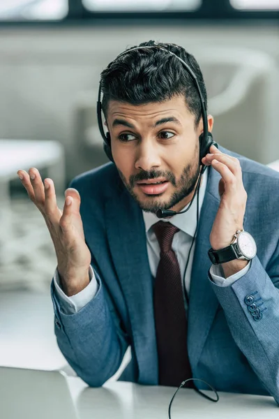 Operador de centro de llamadas desalentado en auriculares que muestran gesto de indignación - foto de stock