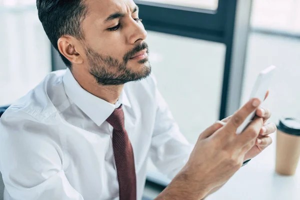 Pensativo hombre de negocios utilizando el teléfono inteligente en la oficina - foto de stock