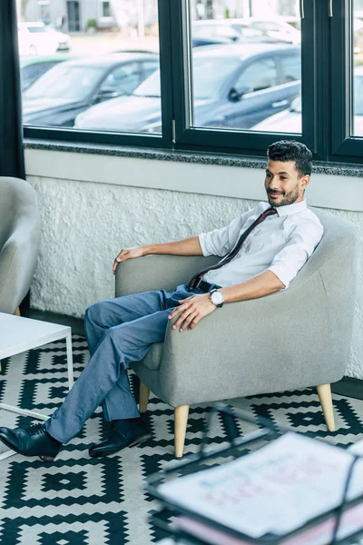 Enfoque selectivo de sonriente hombre de negocios sentado en sillón - foto de stock