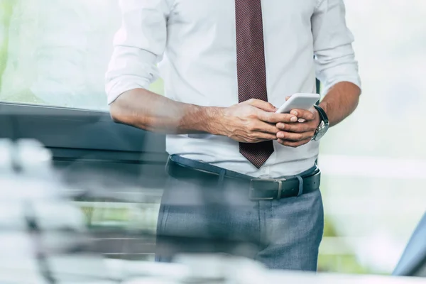 Messa a fuoco selettiva di uomo d'affari utilizzando smartphone in ufficio, vista ritagliata — Foto stock