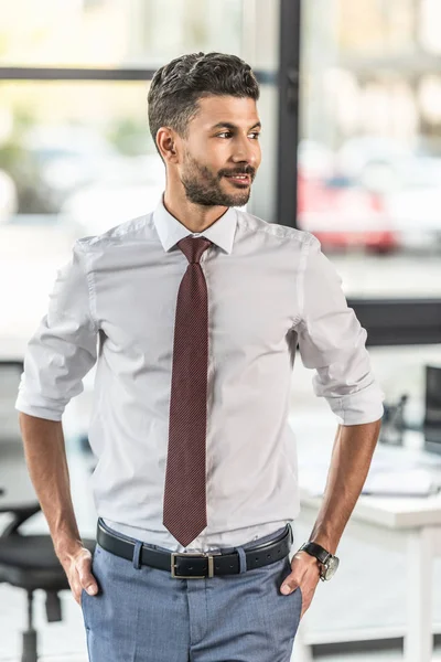 Smiling businessman holding hands in pockets and looking away — Stock Photo