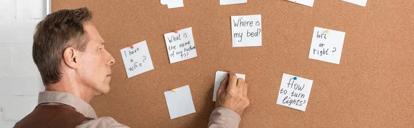 Panoramic shot of retired man with alzheimer disease writing on paper — Stock Photo