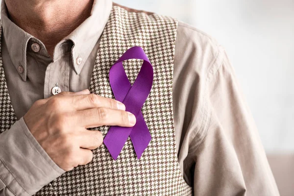 Cropped view of retired man holding purple ribbon — Stock Photo