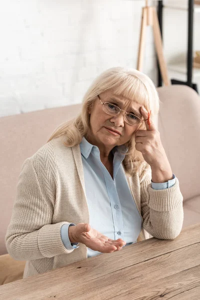 Mujer jubilada con alzheimers enfermedad cadena dedo humano recordatorio mirando a la cámara mientras se toca el templo - foto de stock