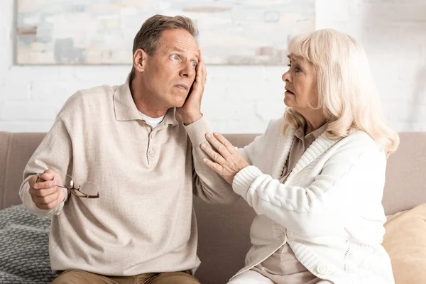 Bouleversé femme âgée regardant mari avec dyslexie toucher le visage — Photo de stock