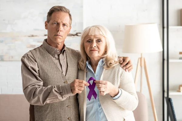 Seniorenpaar steht und hält lila Schleife — Stockfoto