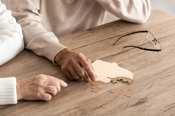 Vue recadrée du couple de personnes âgées près de pièces de puzzle sur la table — Photo de stock