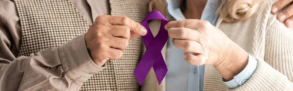 Plano panorámico de hombre y mujer senior sosteniendo cinta púrpura - foto de stock