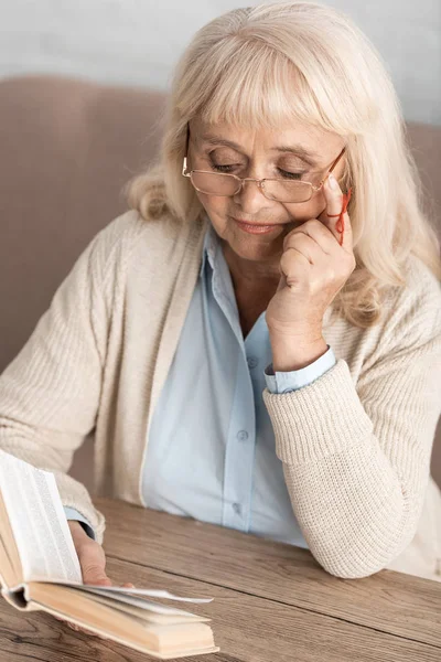 Senior woman with alzheimers disease string human finger reminder reading book while touching glasses — Stock Photo