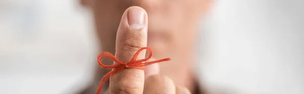 Panoramic shot of retired man with alzheimers disease string human finger reminder — Stock Photo