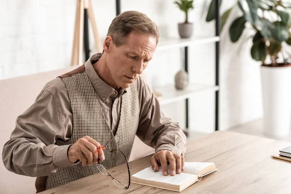 Upset and retired man with alzheimers disease string human finger reminder reading book and holding glasses — Stock Photo