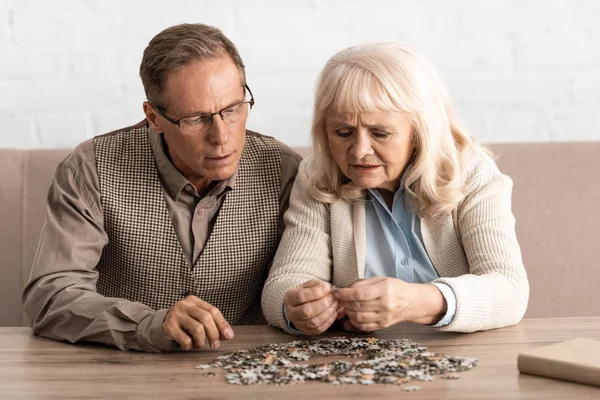 Enfoque selectivo de la pareja de personas mayores con enfermedades mentales juego de piezas del rompecabezas - foto de stock