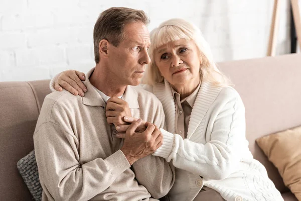 Sad senior woman hugging husband with mental illness at home — Stock Photo