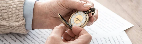 Plan panoramique de l'homme âgé tenant montre de poche près des papiers avec des lettres — Photo de stock