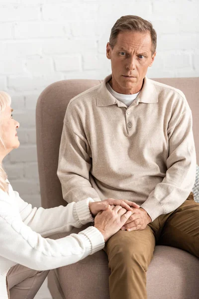 Triste jubilada tocando manos marido con enfermedad mental - foto de stock